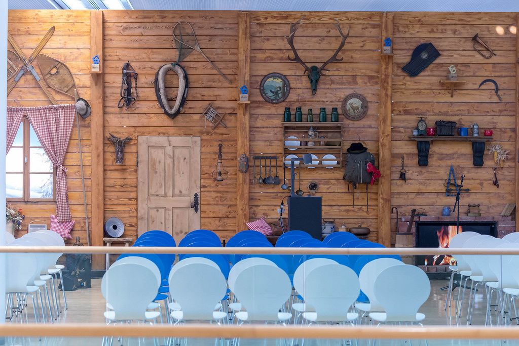 Sitzreihen vor einer im Stil einer bayrischen Berghütte dekorierten Holzwand