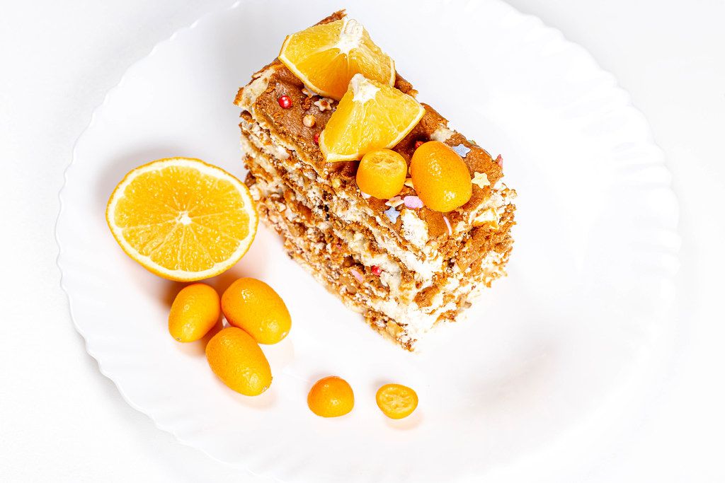 Slice of cake with condensed milk, nuts and citrus, top view