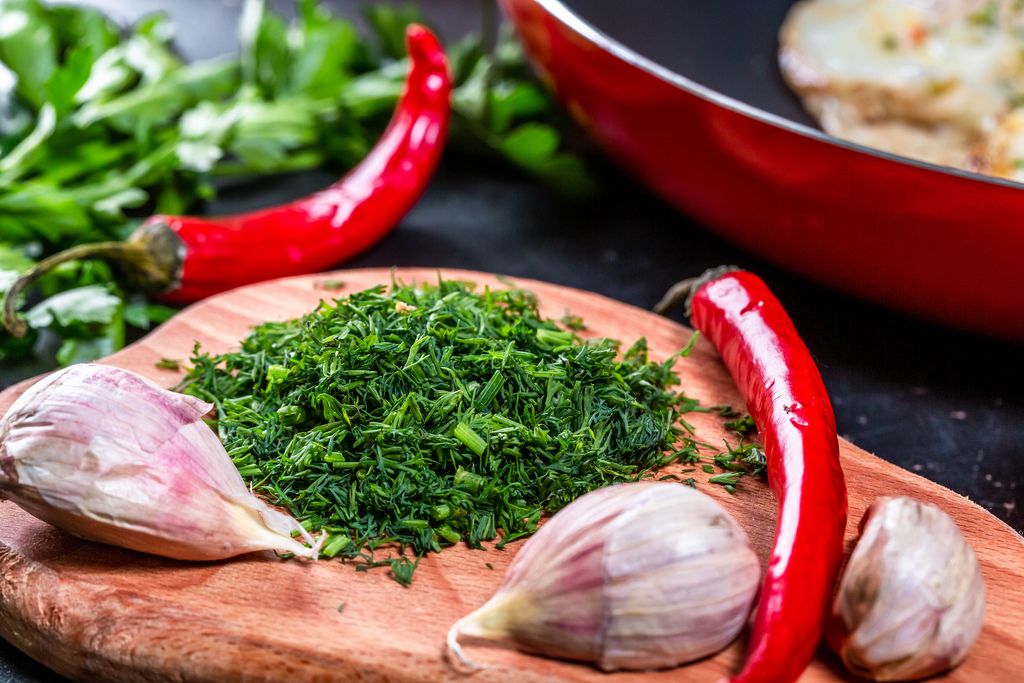 Sliced fresh parsley with garlic cloves and chili pepper on the kitchen Board