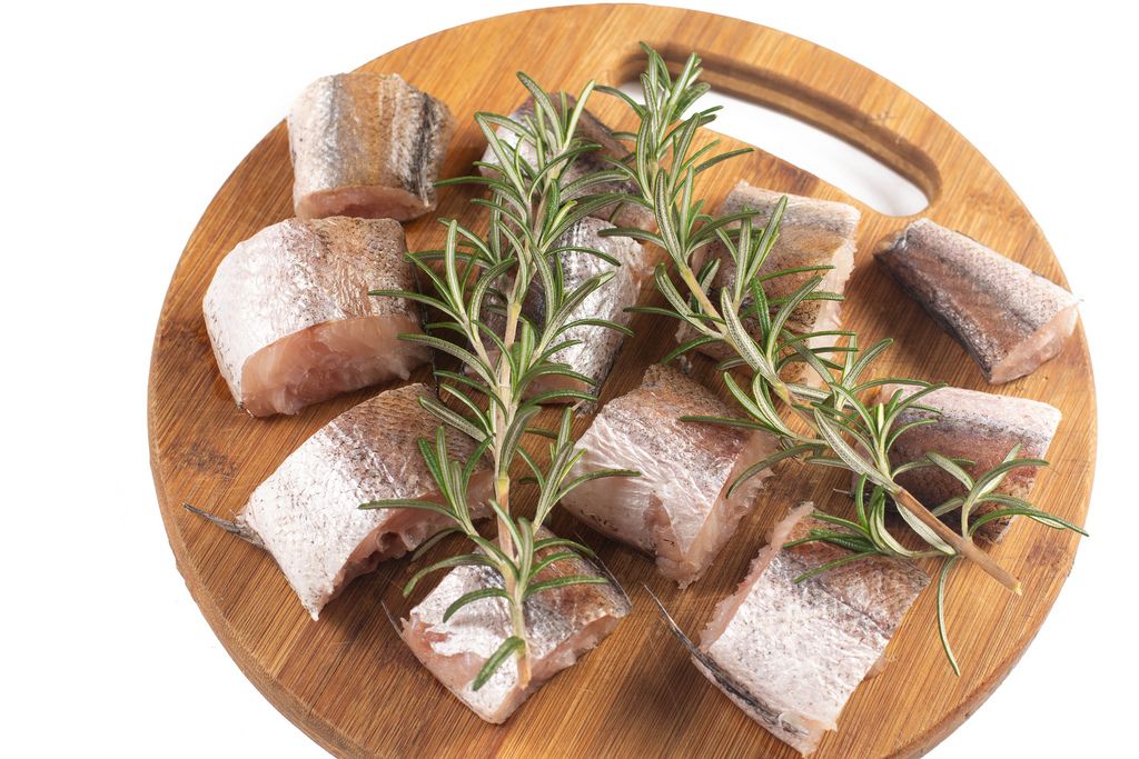 Sliced Hake Fish on the wooden board with Rosemary branches