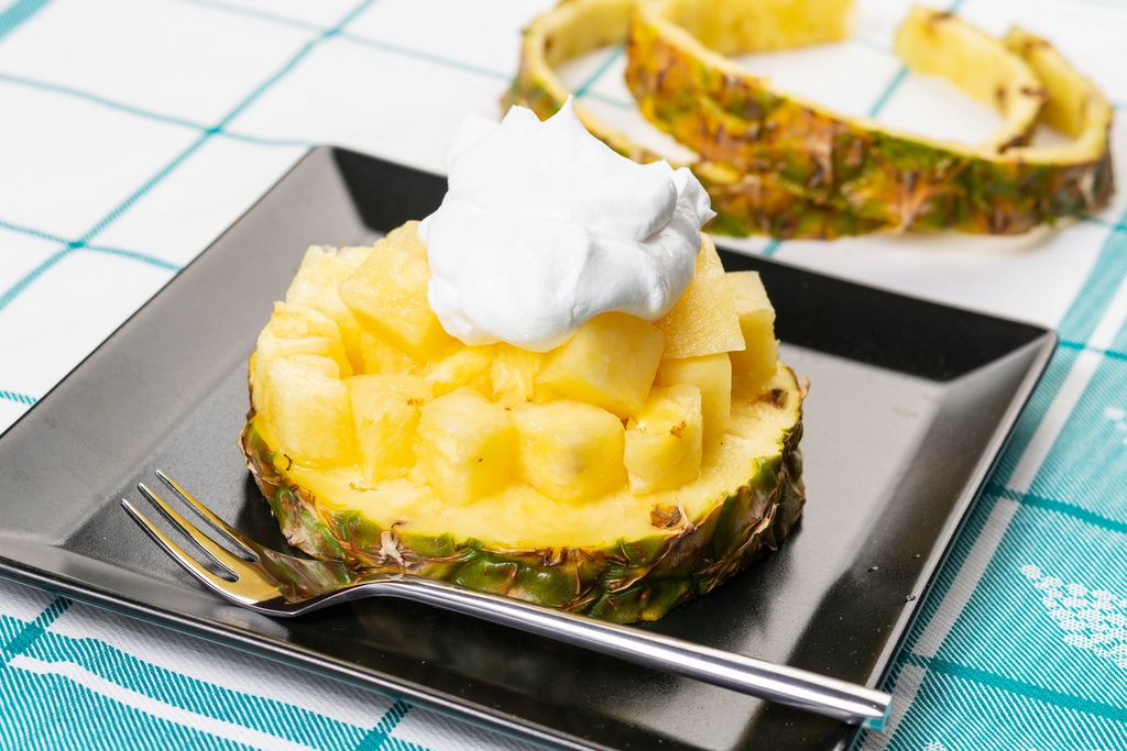 Sliced Pineapple on the plate with pouring cream