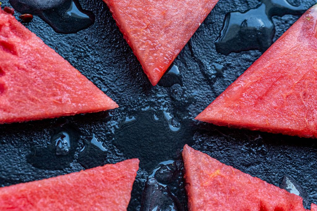 Sliced red sweet watermelon on black stone background