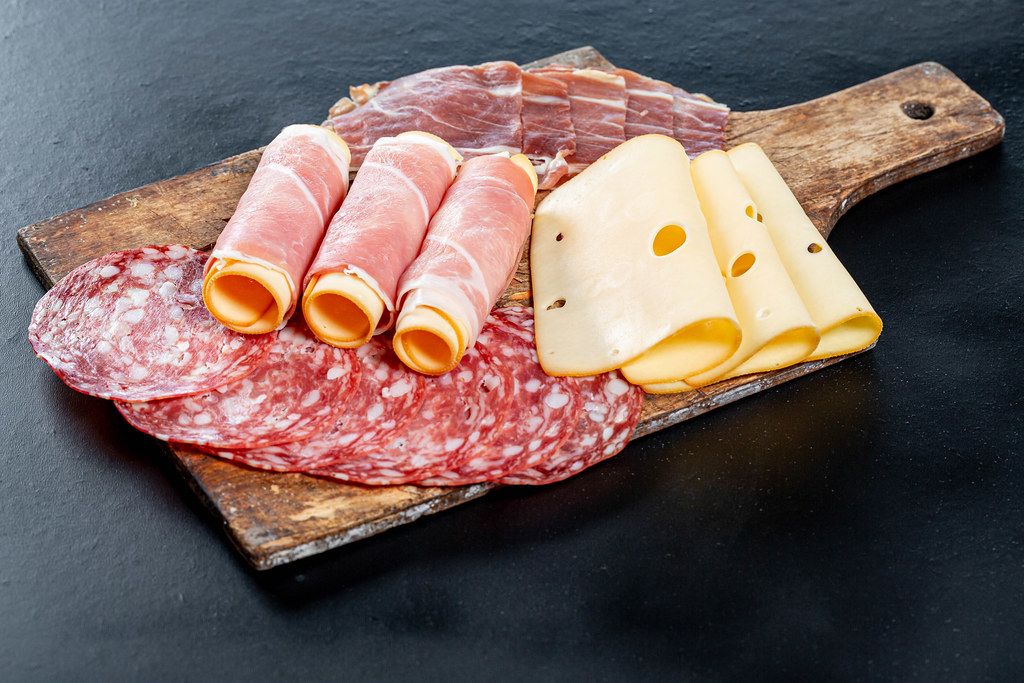 Sliced salami, ham, and cheese on an old kitchen wooden Board on a ...