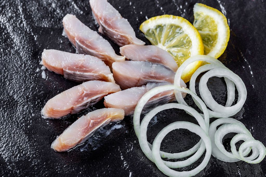 Sliced salted herring with lemon and onion. Top view. Healthy food
