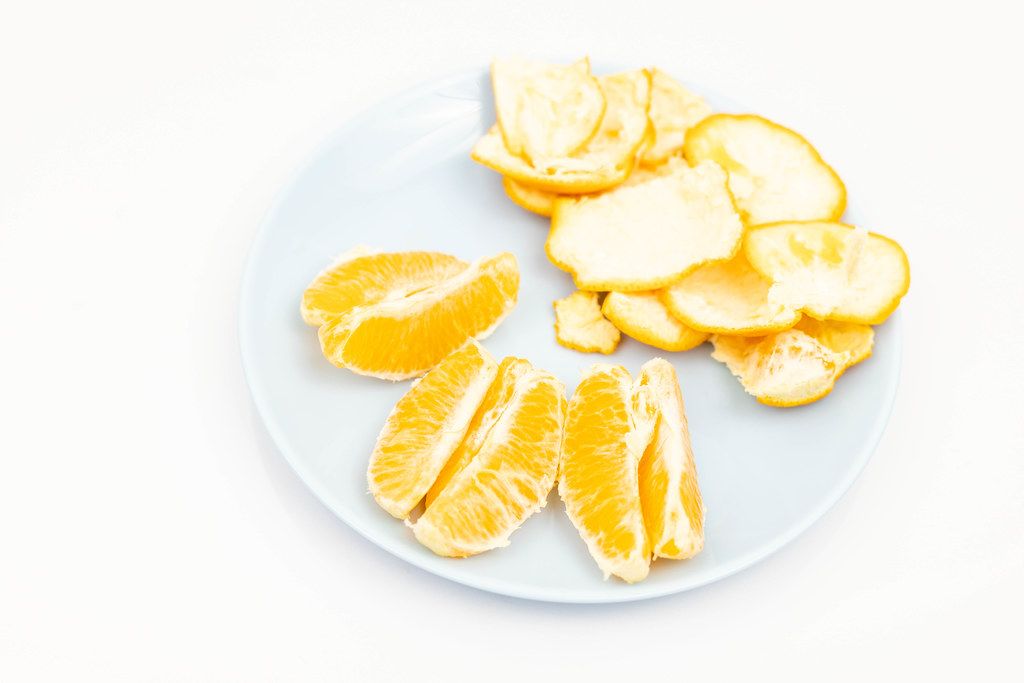 Sliced Tangerine served on the blue plate above white background