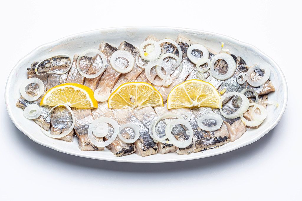 Slices of marinated herring fillet with onion and lemon