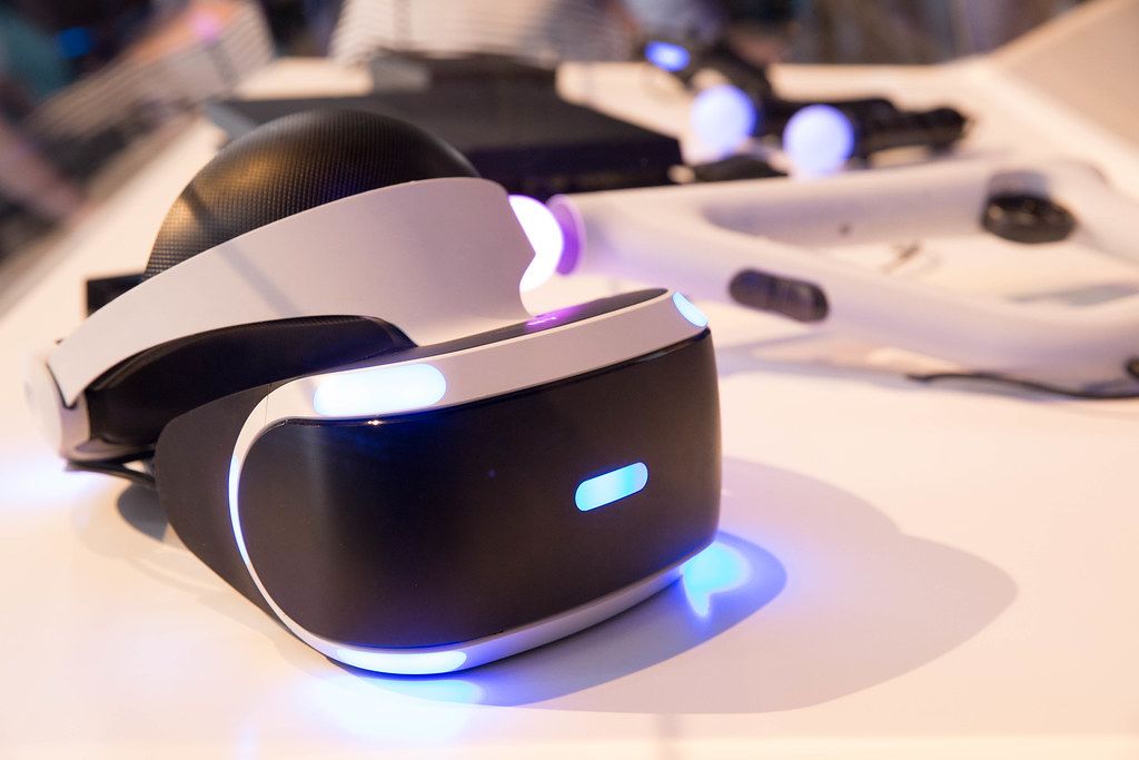 Sony Playstation VR goggles on a white desk with a controller in the background