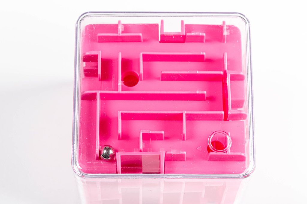Spielzeug Labyrinth-Würfel mit kleiner Kugel vor weißem Hintergrund Draufsicht