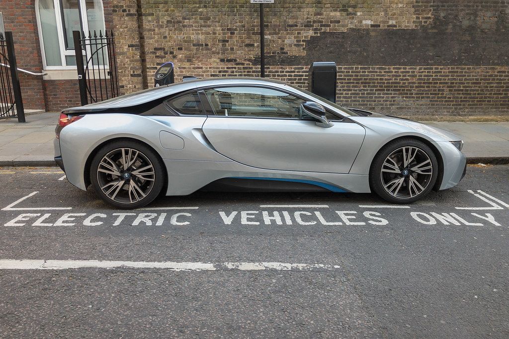 Sports car parked at parking spot for electric vehicles with charging station