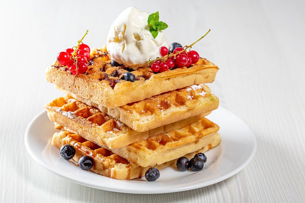 Stack of waffles with fresh berries and ice cream