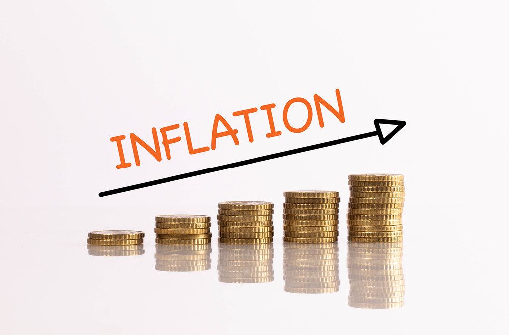 Stapel aus goldenen Münzen mit Pfeil und dem Text Inflation