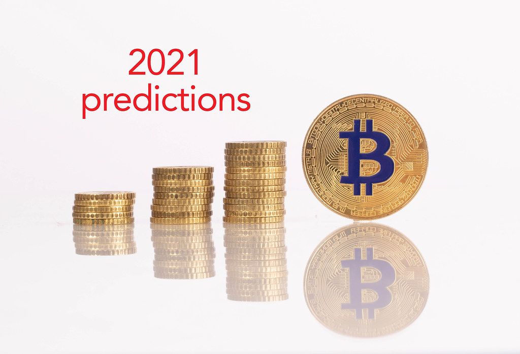 Stapel aus Goldmünzen mit goldener Bitcoin-Münze und 2021 Prognose-Text