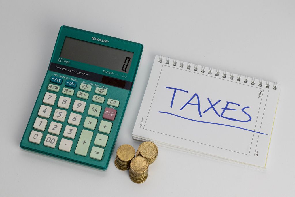 Steuerberechnung - TAXE auf einem Notizblock mit Münzen und einem Taschenrechner