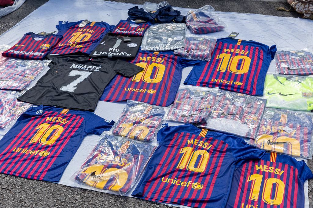 Straßenfhändler verkauft beim Flohmarkt in Spanien Lionel Messi-Trikots vom FC Barcelona und Kylian Mbappé  Merchandise