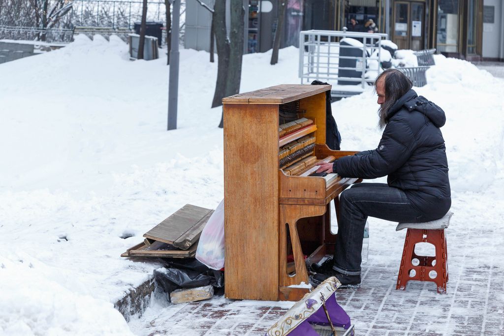 Straßenmusiker spielt auf Piano im Schnee in der Stadt