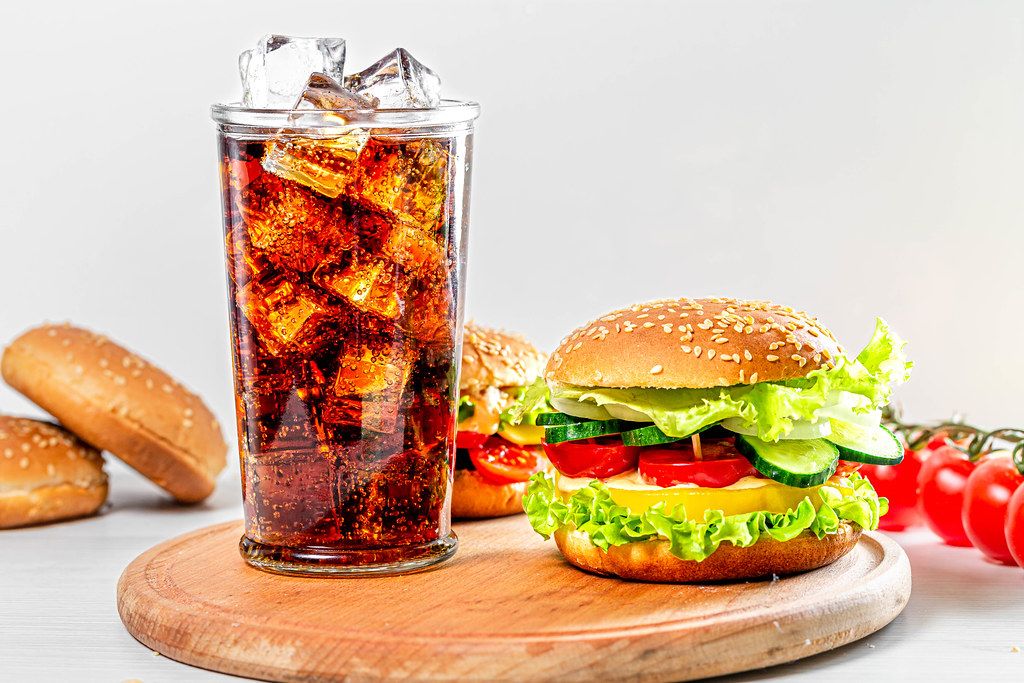 Street food concept - a glass of Coca Cola and hamburgers on a white wooden table (Flip 2019)