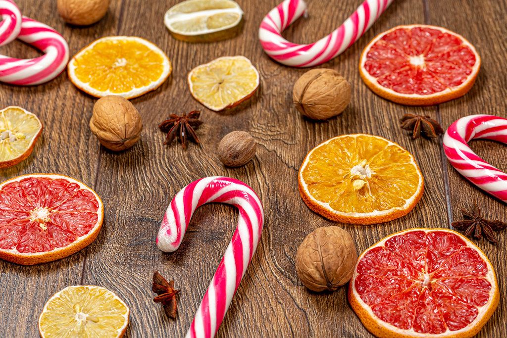 Sweet Christmas cane-lollipops with pieces of dried citrus and nuts