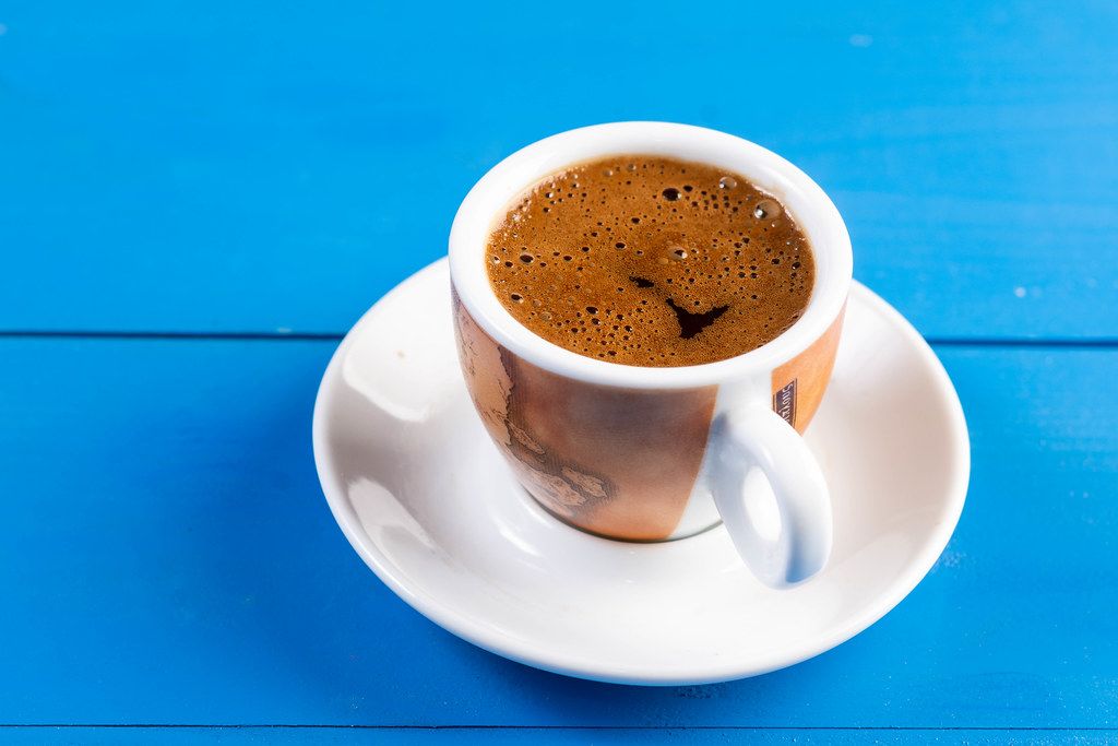 Tasse Kaffee mit Untertasse auf einem blauen Holztisch