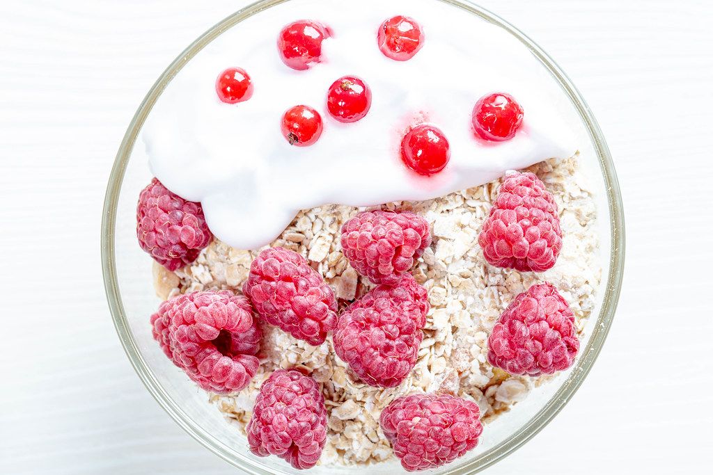 Tasty oatmeal porridge with raspberries and red currant, close up view (Flip 2019)