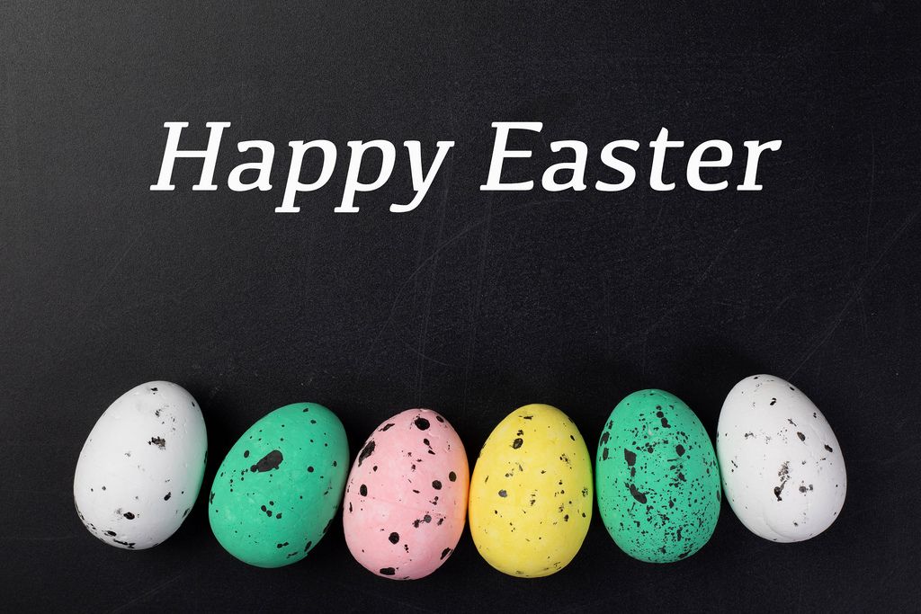 Text HAPPY EASTER (frohe Ostern) über Reihe aus bunten Ostereiern vor schwarzem Hintergrund