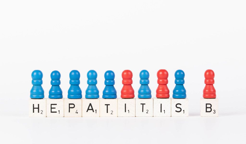 Text Hepatitis B written on wooden blocks with pawns in various colors on white background