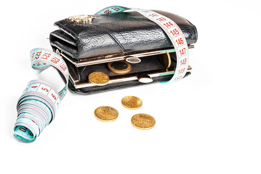 The concept of crisis, lack of money, loss of financial stability - wallet with coins and a measuring tape