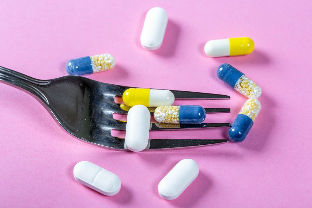 The concept of drug nutrition-encapsulated medicines with a fork on a pink background