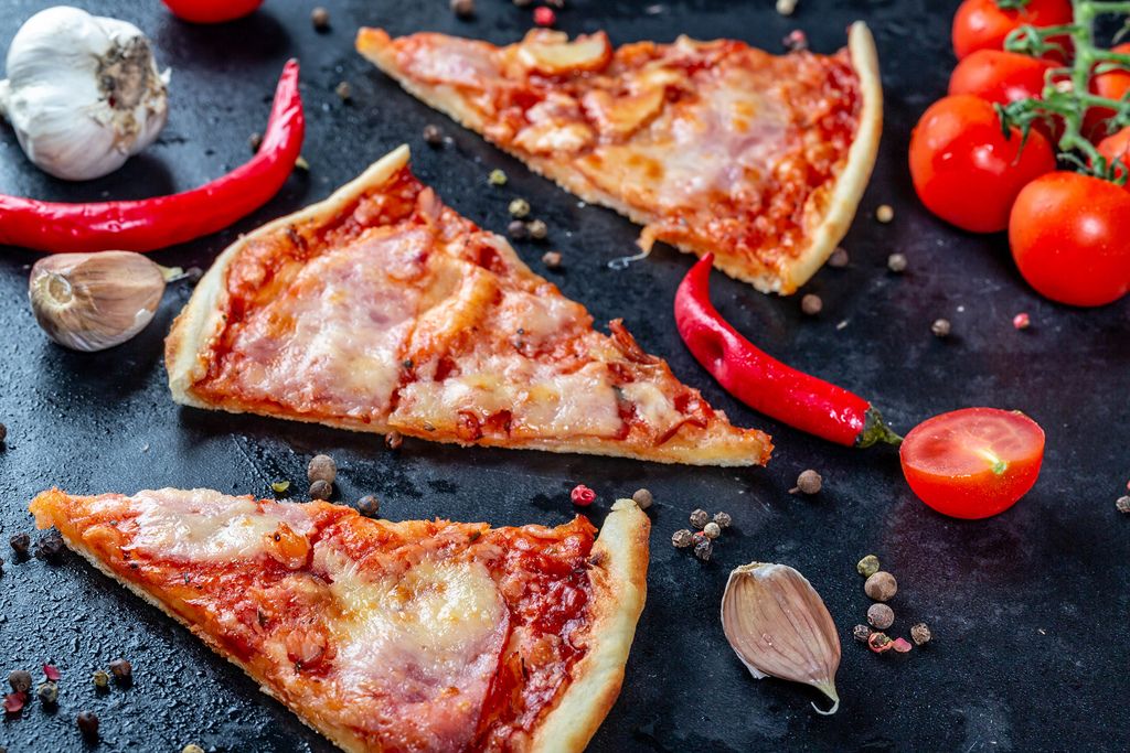 Three slices of pizza with bacon and tomato sauce with spices on a black background