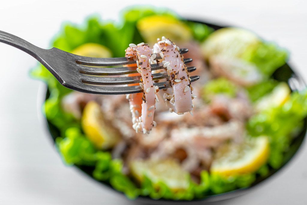 Tintenfischringe auf einer Gabel, mit einem gesunden Salat im ...