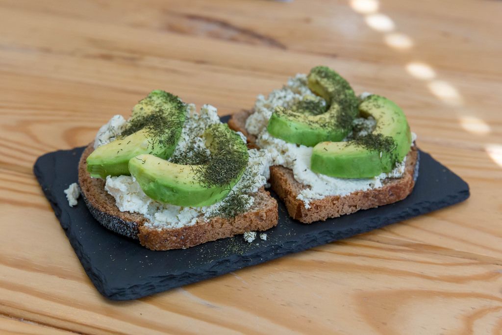 Toast with ricotta, dill and avocado served on stone serving plate