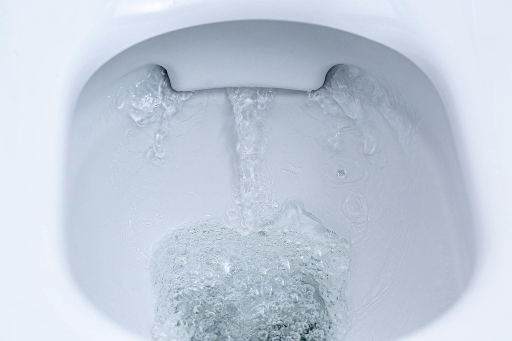 Toilet bowl flushing water in bathroom close up