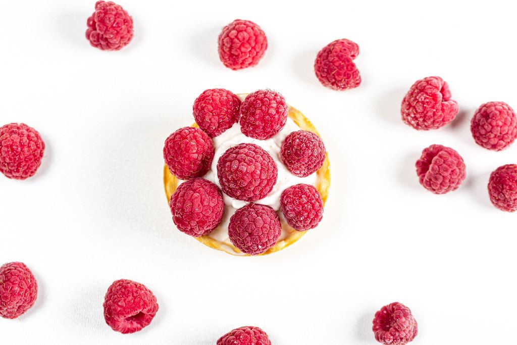 Top view, cake with whipped cream and raspberries on a white background