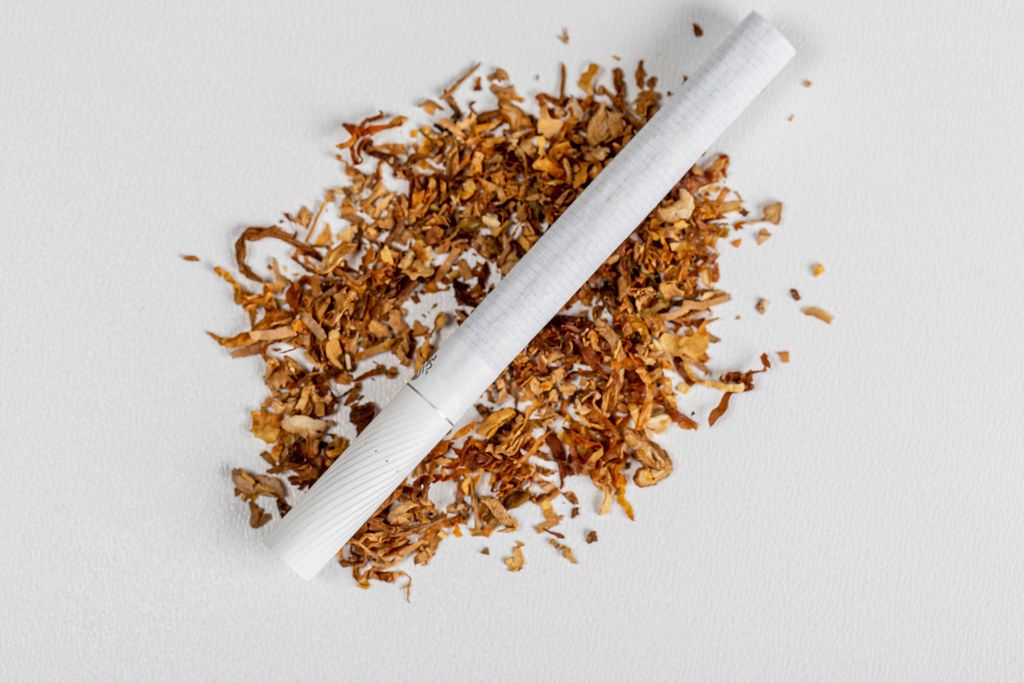 Top view, cigarette on and dry tobacco on white background