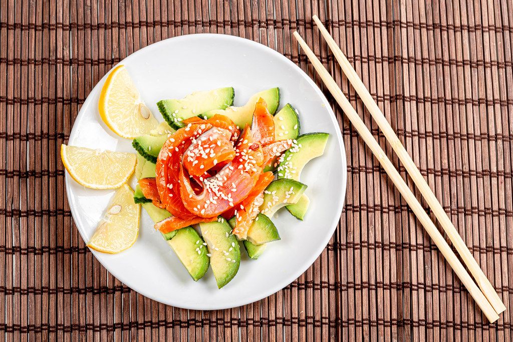Top view, diet salad with smoked salmon, avocado and sesame seeds