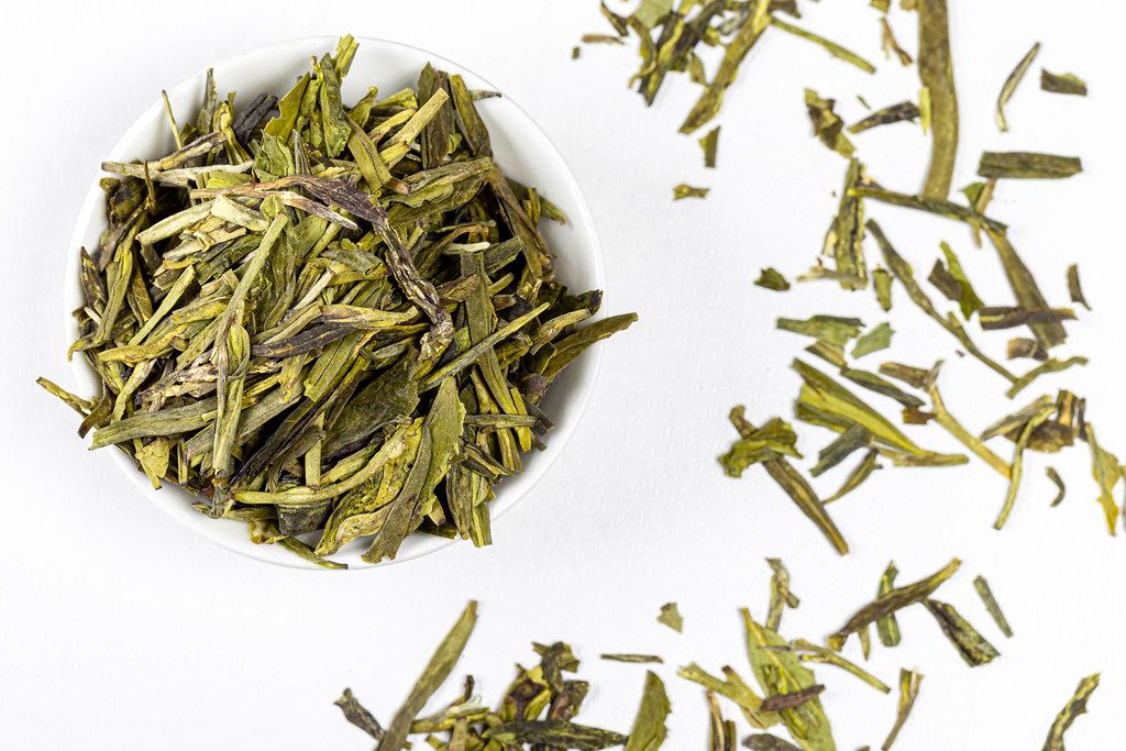 Top view, dried green tea leaves on white background (Flip 2020)