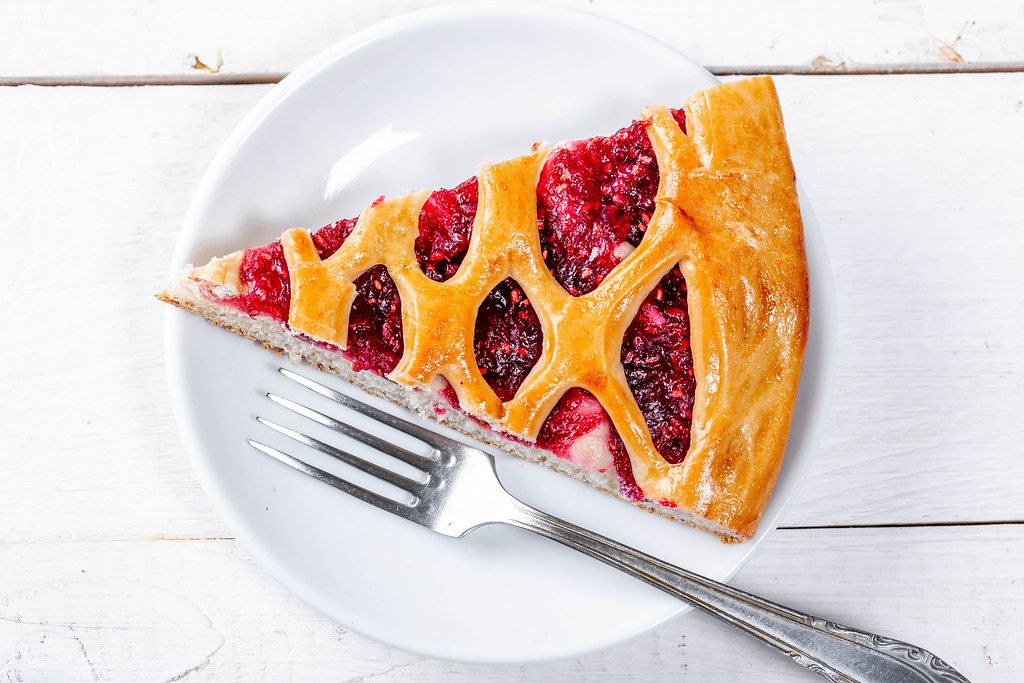 Top View Food Photo of a Raspberry Pie on a Plate with Fork on White Wooden Background