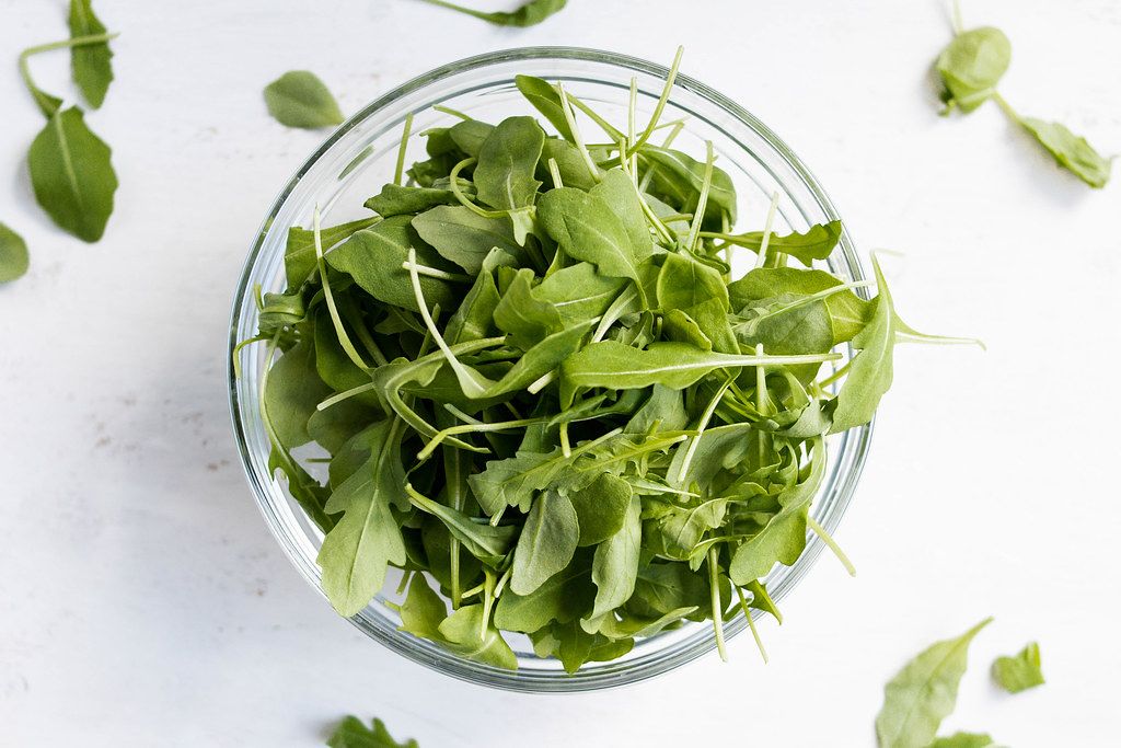 Top View Healthy Food Photo of Fresh Arugula in Glass Bowl on white Background