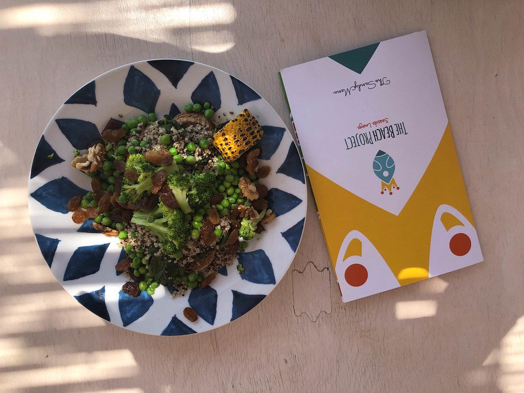 Top view of a colorful menu of Beach Project Restaurant in Greece, next to the meatless healthy meal Veggie Bowl with greens, corncobs & nuts