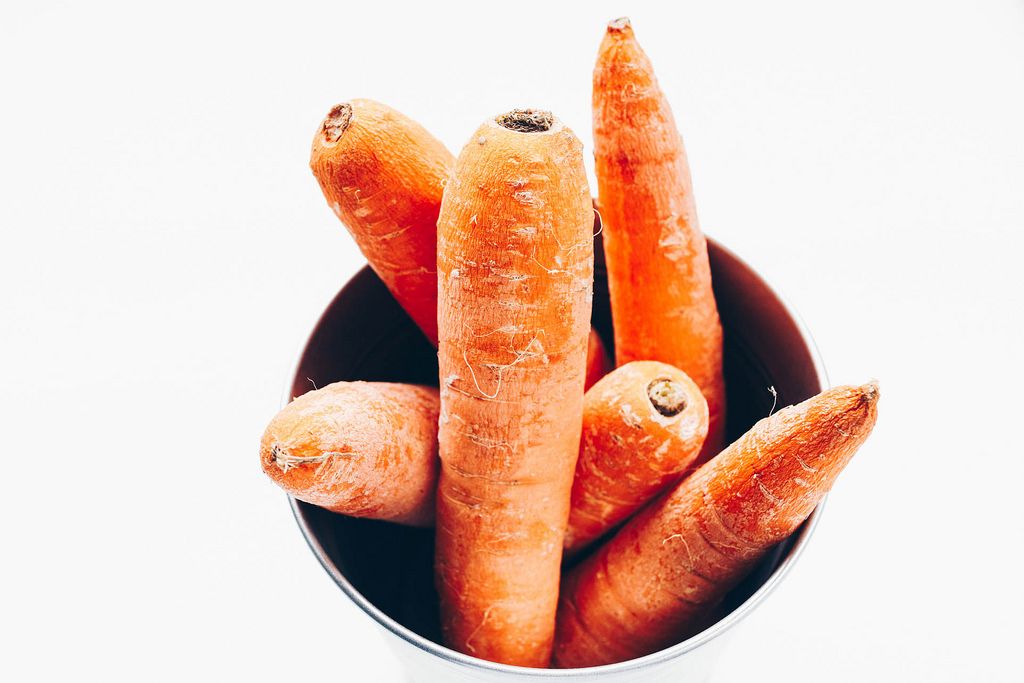 Top view of carrots in a bowl. White background . Close up