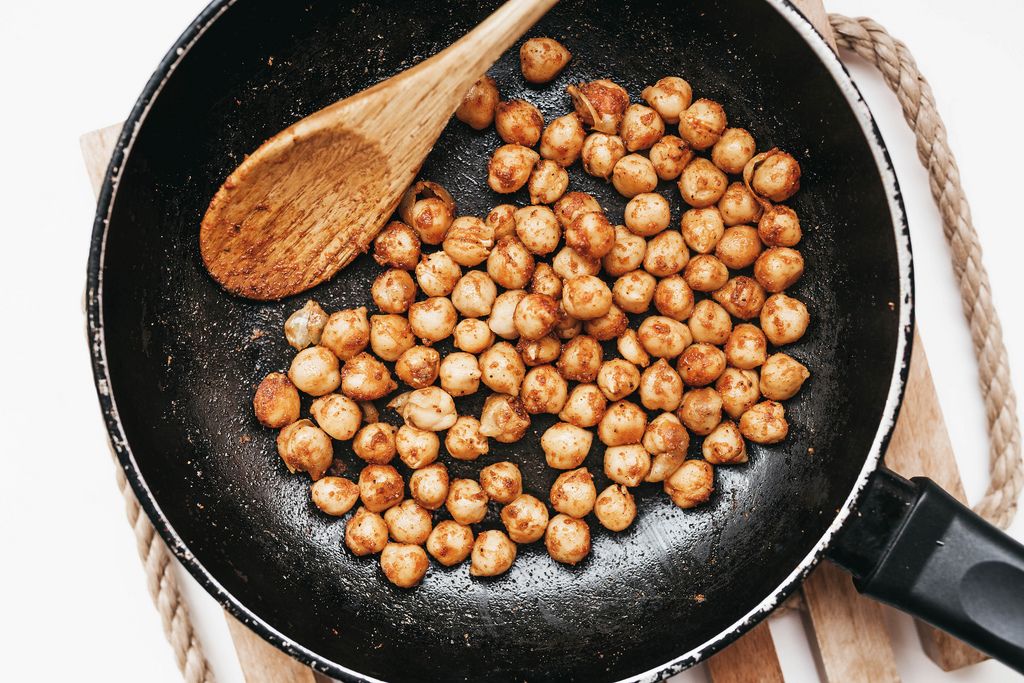 Top view of chickpeas roasted in pan with spices and wooden spoon