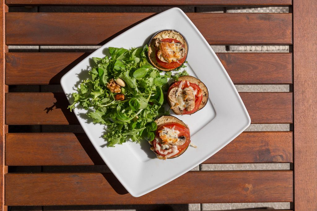 Top view of eggplant and tomatoes with cheese spread and salad with nuts