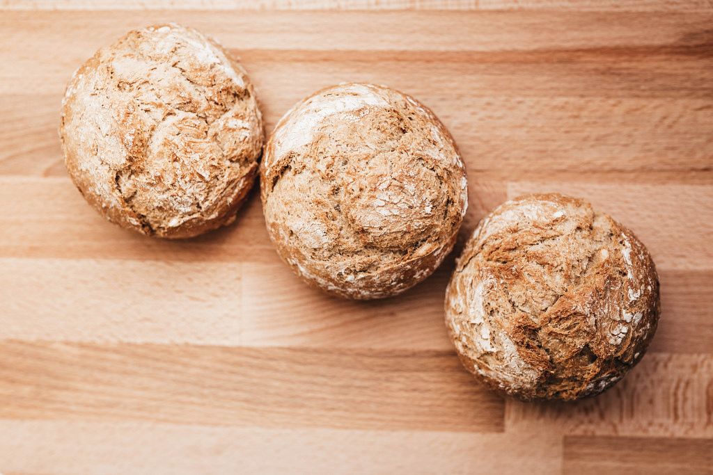 Top view of fresh baked wholemeal crusty bread rolls on a wooden board