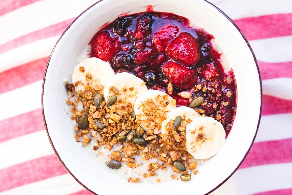 Top view of oatmeal bowl with banana, berry compote and granola topping