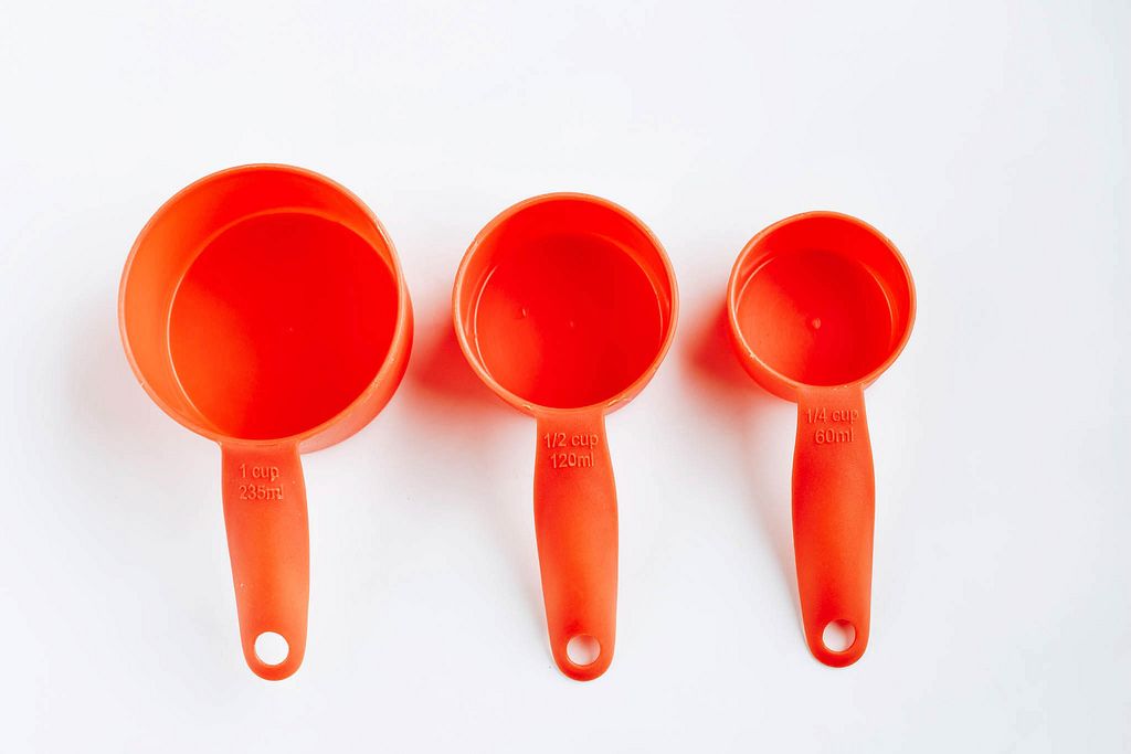 Top view of orange plastic measuring cups on white background.