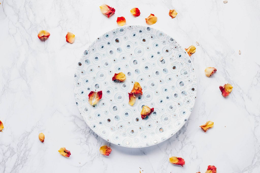Top view of printed plate with rose petals. Flat lay. Marble background