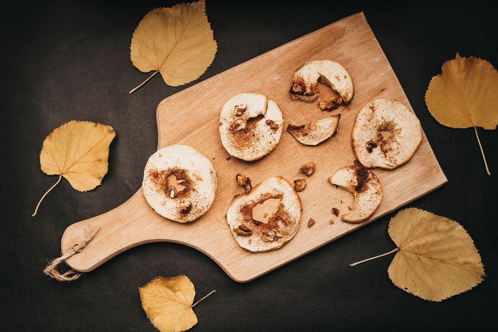 Top view of wooden board with roasted apples with walnuts, honey and cinnamon