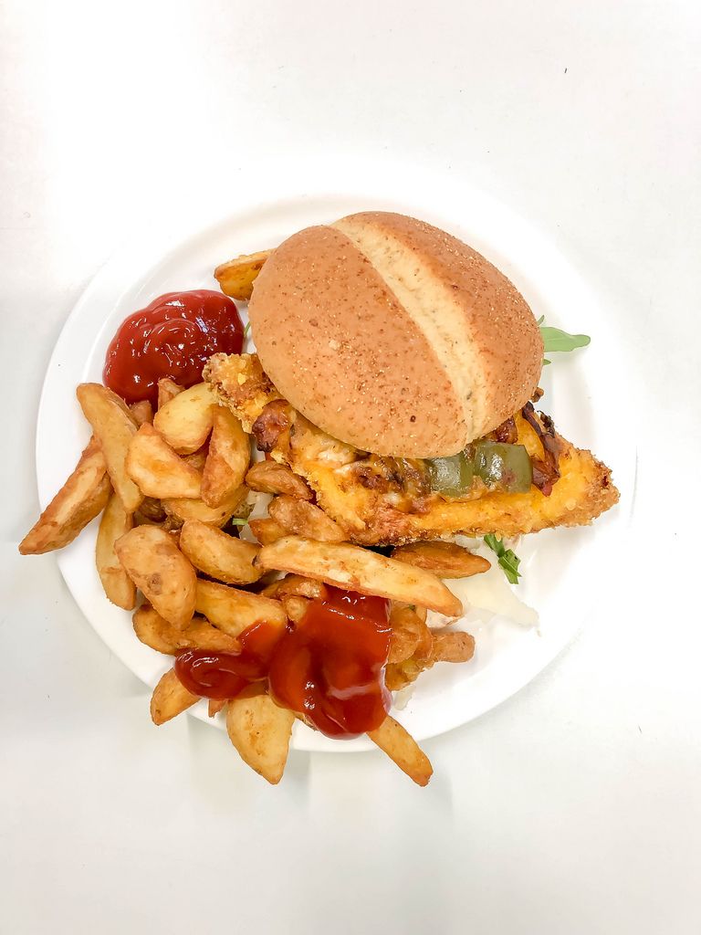 top view on plate with hamburger with breaded patty, aubergine, rocket salad and parmesan cheese, as a side dish crispy deep fried french fries with ketchup on white background