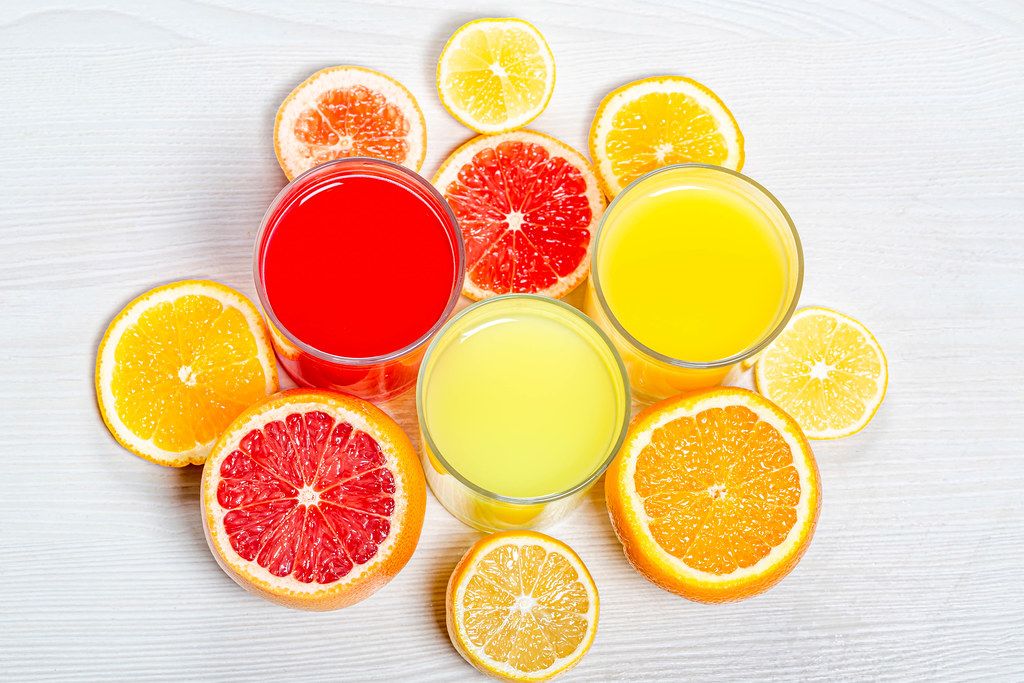Top view orange, lemon and grapefruit juices with slices of fresh citrus