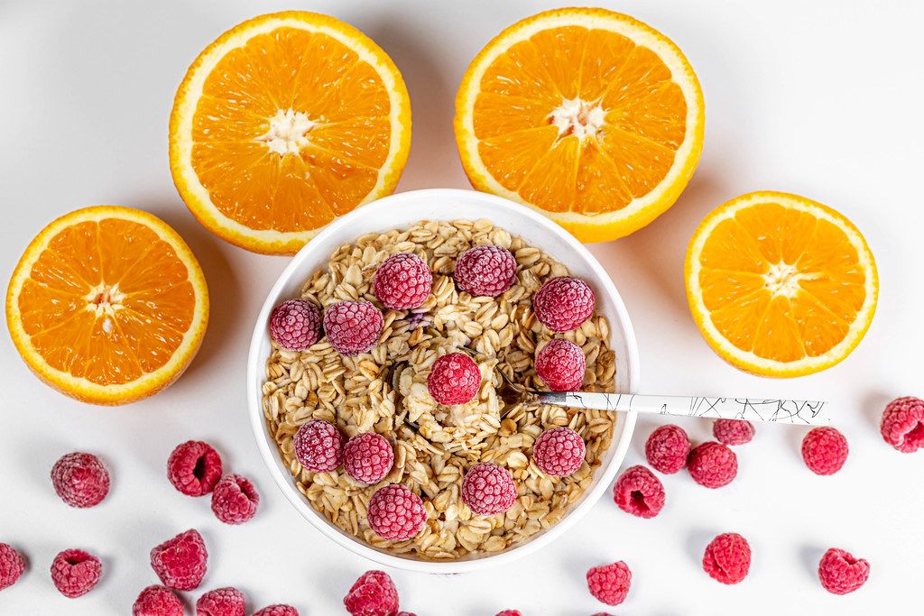 Top view, porridge with raspberries and oranges on a white background