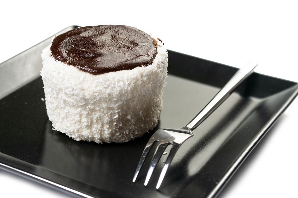 Törtchen mit Kokosstreuseln und Schokoladenglasur auf schwarzem eckigem Teller